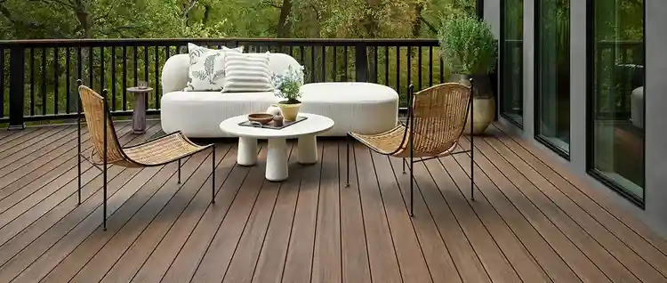 Brown deck with high color variation has a modern outdoor lounge couch and two wicker arm chairs