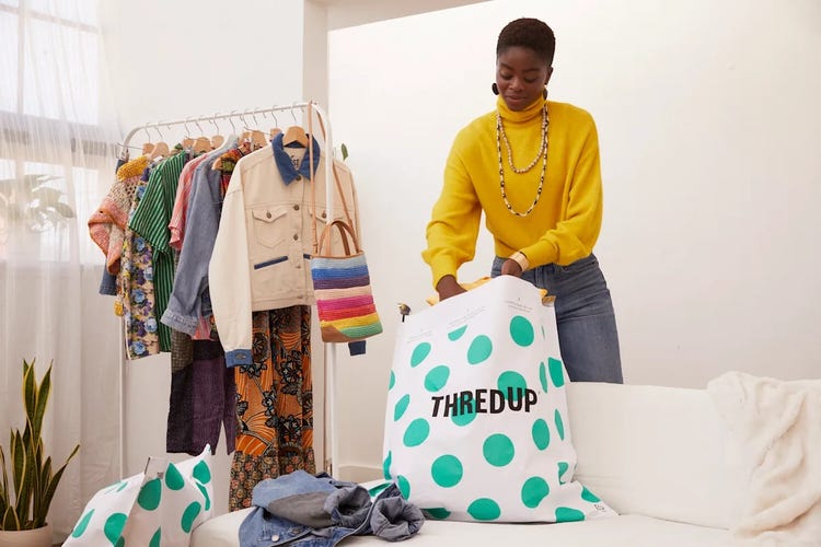 A woman holds a bag filled with clothes, standing in a casual setting.