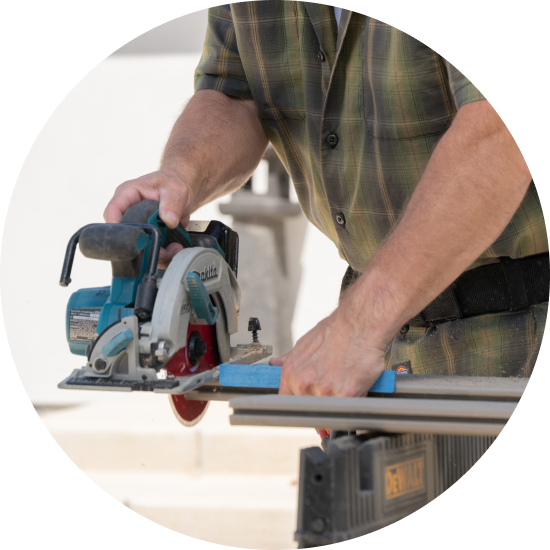A person uses a circular saw to cut a deck board