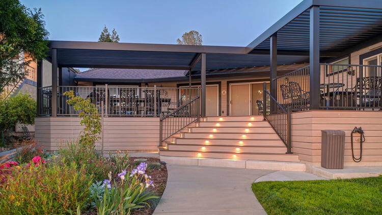 Lume Deck Lights riser lights glowing on AZEK Landmark Collection deck stairs in French White Oak with an American Walnut picture-frame border, photographed at dusk on a lakefront home on Lake of the Pines in Auburn, California. Built by Stone Ridge Decking — custom decks across Northern California, serving Granite Bay, Folsom, Roseville, Lake Tahoe, Auburn, Sacramento, and Grass Valley. https://stoneridgedecking.com