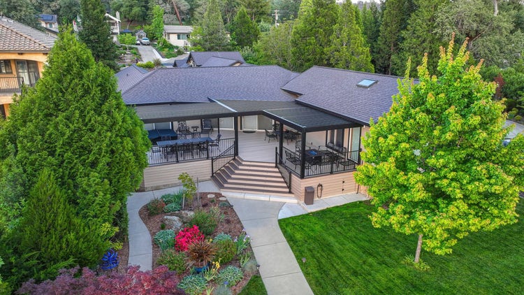 Aerial / drone view of an AZEK Landmark Collection deck in French White Oak with American Walnut picture-frame border, a 4K aluminum slatted pergola in matte black, TimberTech Fulton Rail Steel, a sunken hot tub, and a private dock — on a lakefront lot on Lake of the Pines in Auburn, California, photographed at golden hour. Built by Stone Ridge Decking — custom decks across Northern California, serving Granite Bay, Folsom, Roseville, Lake Tahoe, Auburn, Sacramento, and Grass Valley. https://stoneridgedecking.com