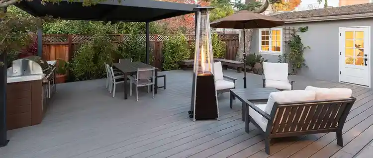 Outdoor deck in the shade at sunset with a heat lamp near two outdoor seating areas