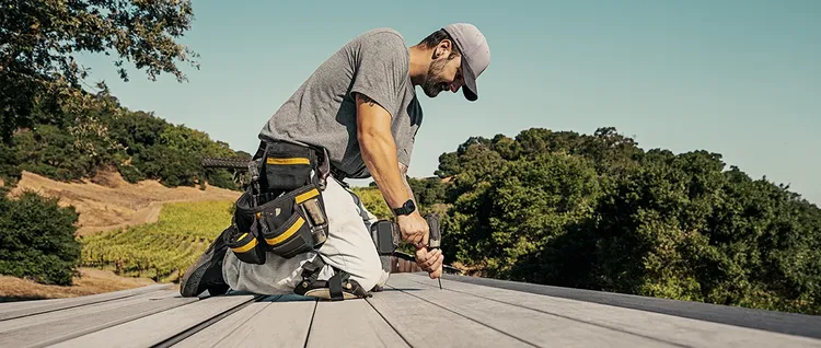 Deck contractor drills a screw into a deck board at a job site