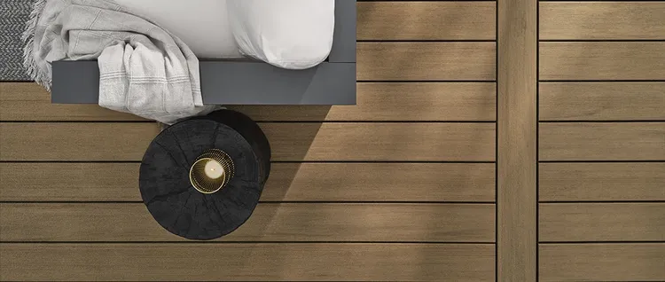 Overhead view of the edge of a couch on tan deck in the shade