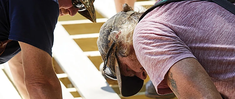 Deck contractor leans over to install deck board