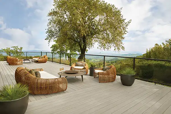 Multiple wicker furniture outdoor living room areas on a light tan deck