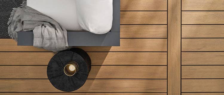 Overhead view of a tan deck with an arm chair draped with a blanket and a circular side table