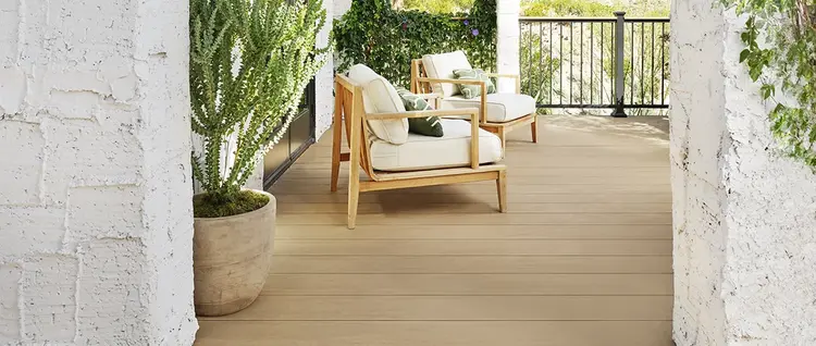Two modern wooden armchairs are on a tan deck in the southwest