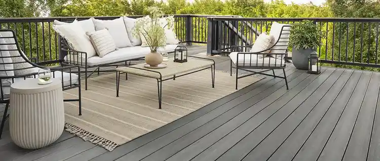 A TimberTech Composite Deck from the Prime+ Collection in the color Sea Salt Gray. Features stylish deck furniture on top of an outdoor rug.