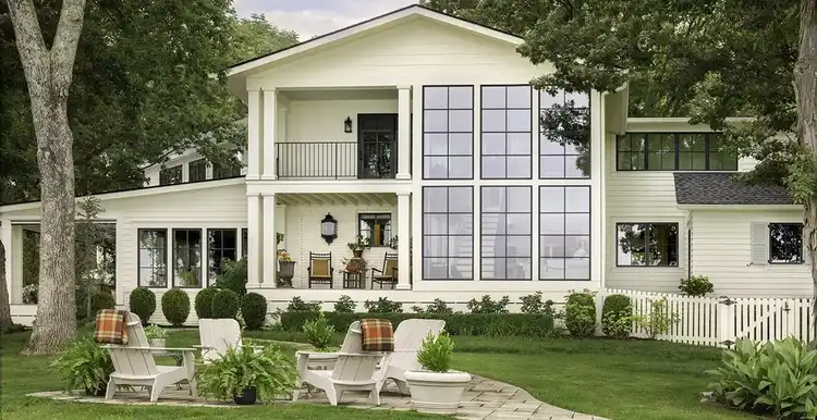 View of the back of the house with giant windows and a fire pit in the yard