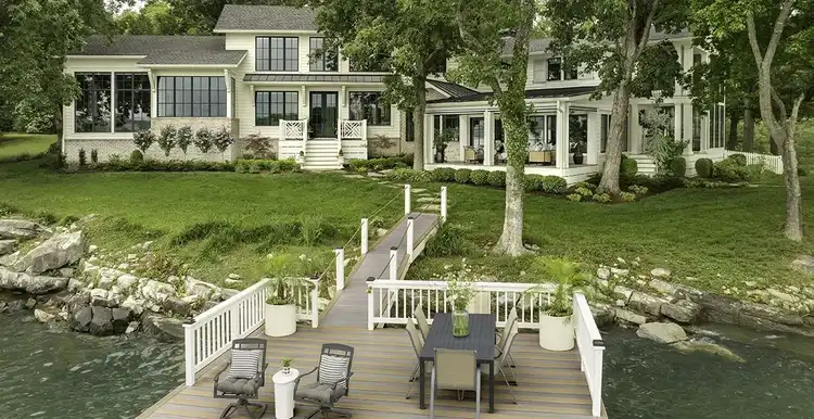 Side entrance of house in the background while the foreground shows a large dock on the lake built with two-toned TimberTech decking