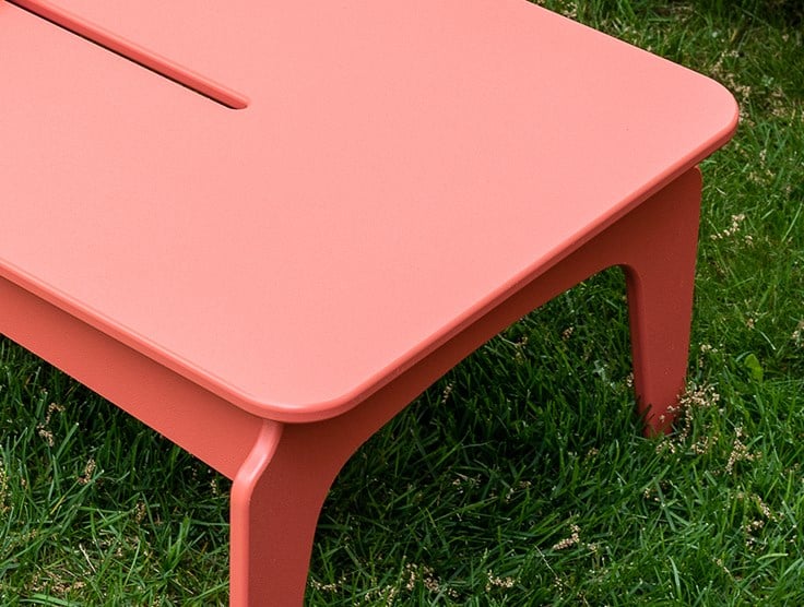 Red footstool over vibrant green grass
