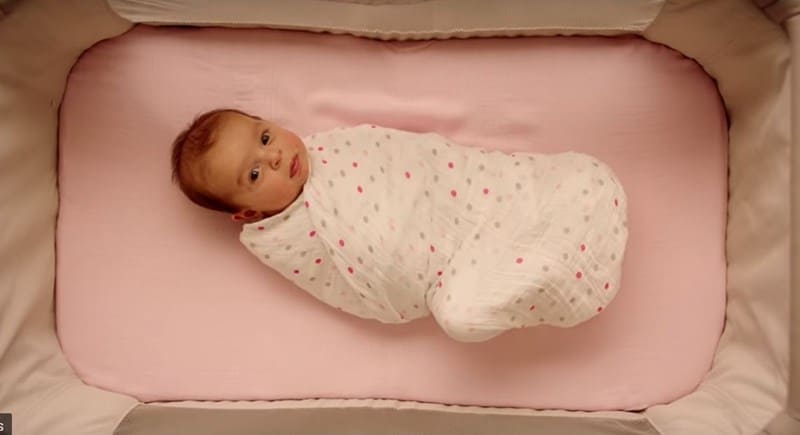 a swaddle baby laying in bed