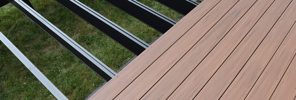 Aluminum substructure is visible on an unfinished deck with brown composite decking partially installed.
