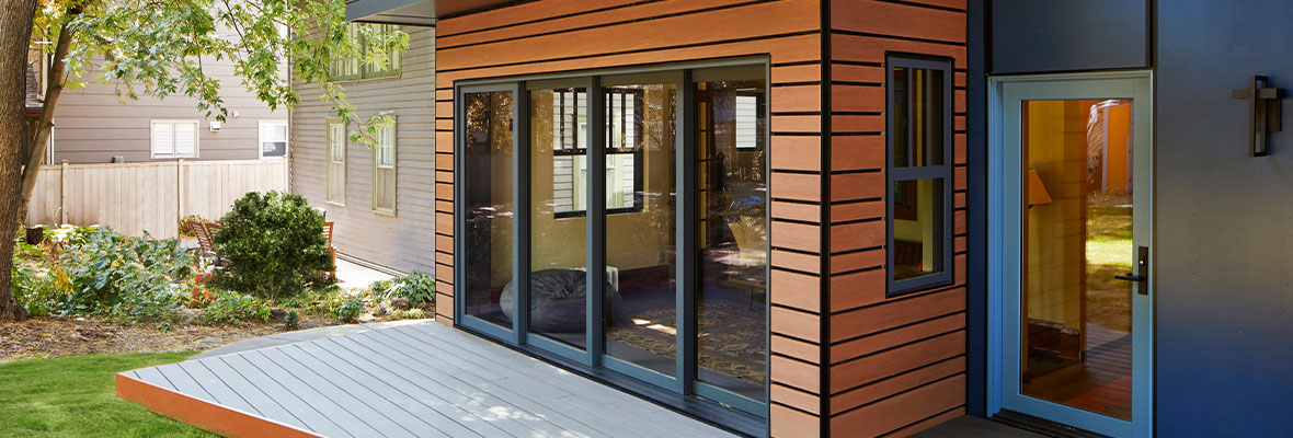 A gray deck with orange rim boards compliments a bold blue and orange home exterior.