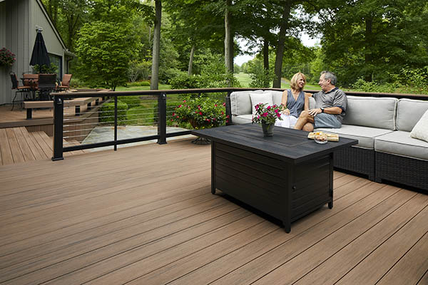 Decking boards featuring TimberTech AZEK Vintage Collection in English Walnut with Couple sitting on outdoor furniture