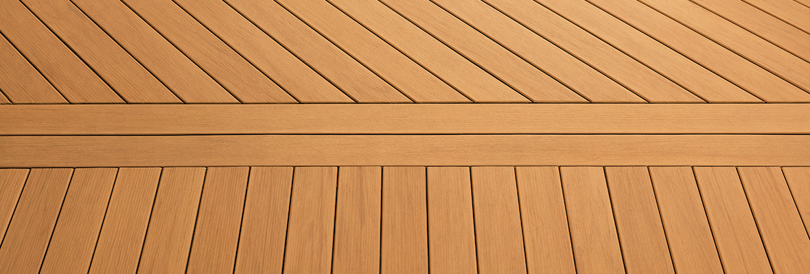 A close up of composite decking with two horizontal middle boards and diagonal boards installed above with vertical boards below.