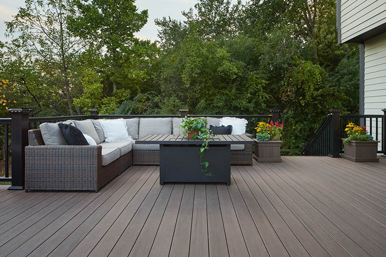 Deck board spacing between deck boards with l-shaped couch and end table on composite deck