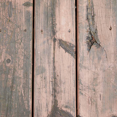 Inspect a wood deck surface for cracks and splintering