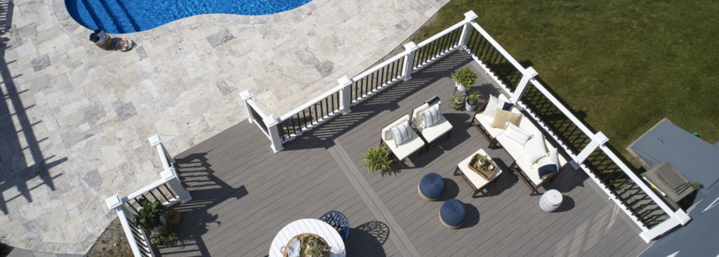 Deck ideas with a furnished poolside composite deck on sunny day