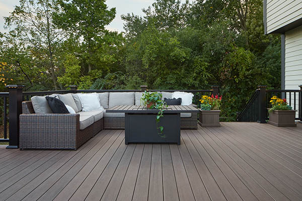 Composite decking vs wood and wood deck vs composite deck featuring l-shaped wicker couch and end table on composite deck