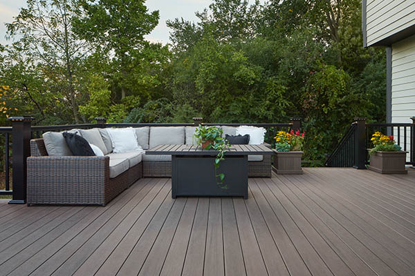 Composite decking vs wood and wood deck vs composite deck featuring l-shaped wicker couch and end table on composite deck