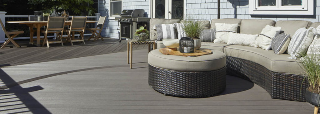 Composite decking vs wood and wood deck vs composite deck featuring furnished deck behind blue home with ottoman