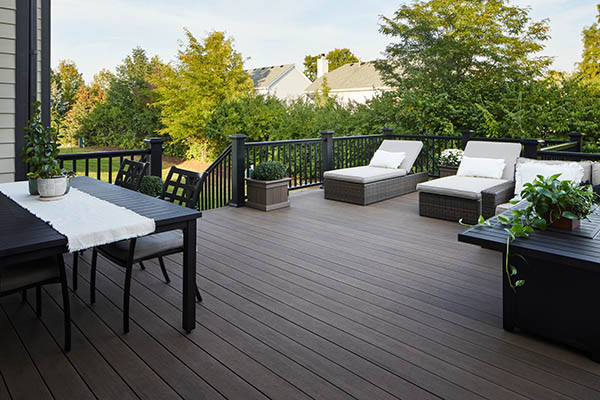 Deck over concrete patio with shady furnished outdoor deck and lush lawn