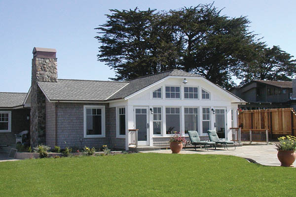 Deck over concrete with gray house and manicured lawn