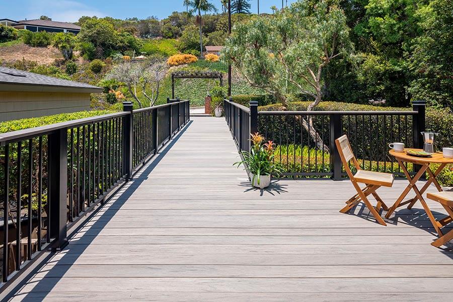 Deck railing ideas and deck baluster ideas on sunny composite wood walkway with lush surroundings