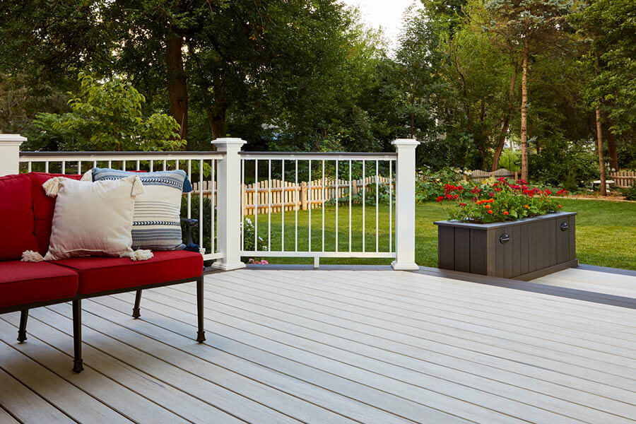 Red couch on round composite deck in lush backyard