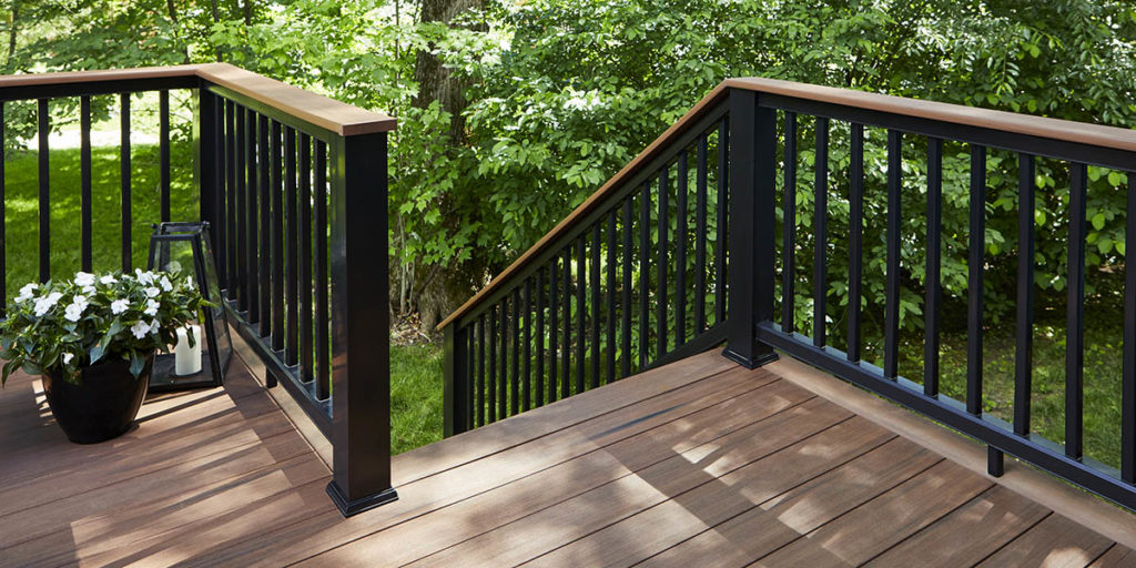A composite deck built in a wooded area with richly hued decking