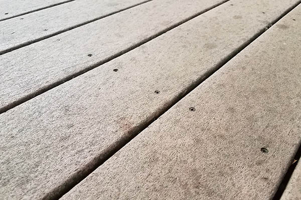 Close up shot of uncapped composite deck boards showing signs of fading