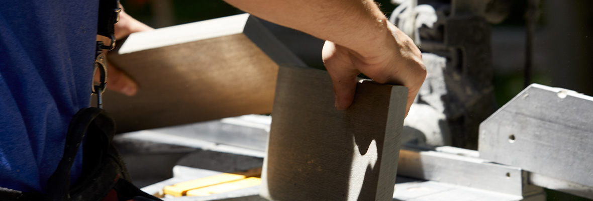 A close up shows a White Oak deck board cut in two and a contractor separating the pieces.