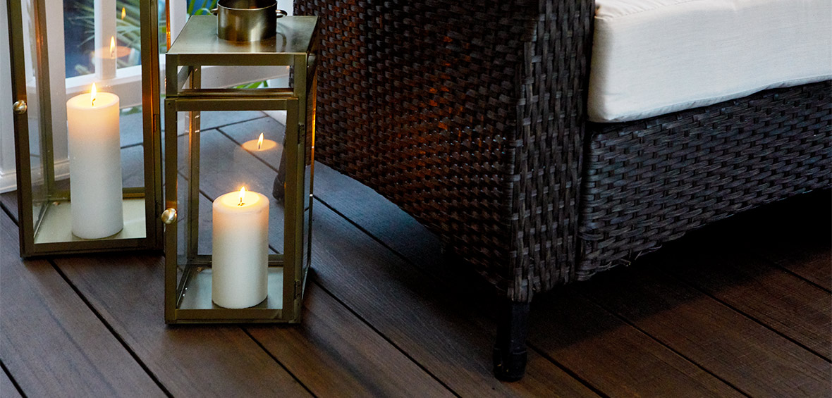 White candles burning in bronze deck lanterns next to a chair. 