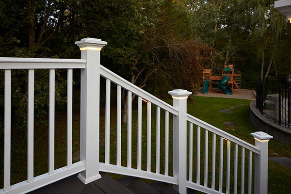 Lights for deck railing posts along a curved white composite railing