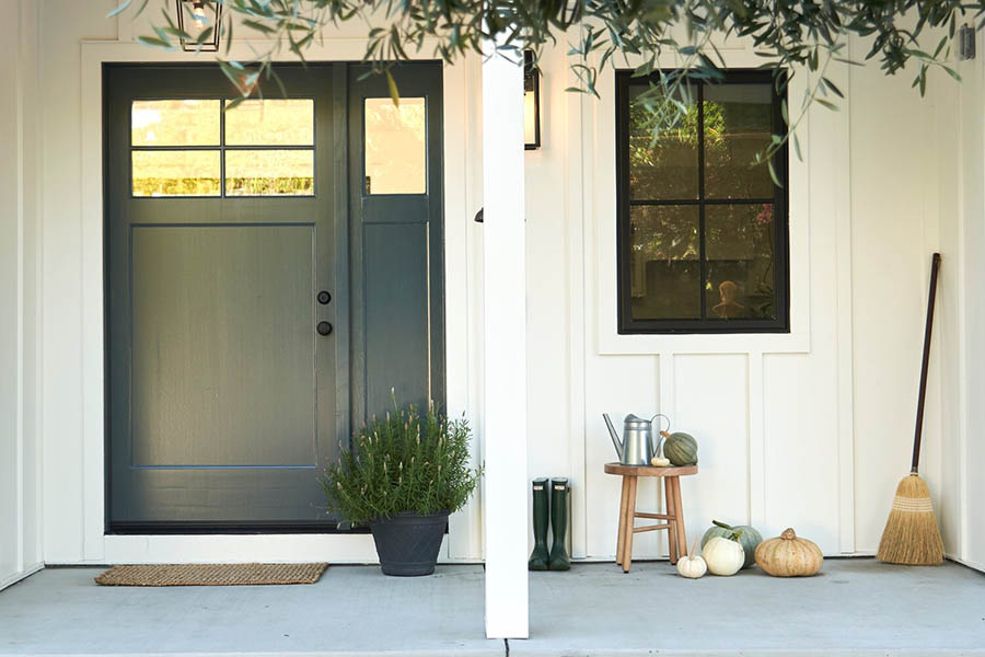 Modern farmhouse-style front porch designs feature functional decor like a wood stool