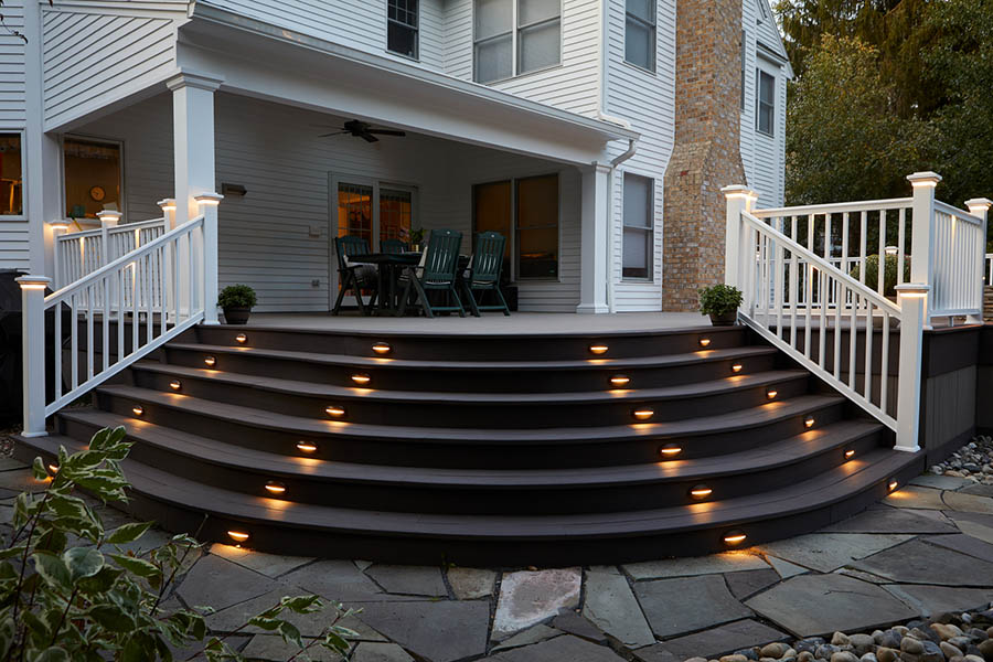Outdoor deck lighting ideas include riser lights in a set of cascading curved stairs