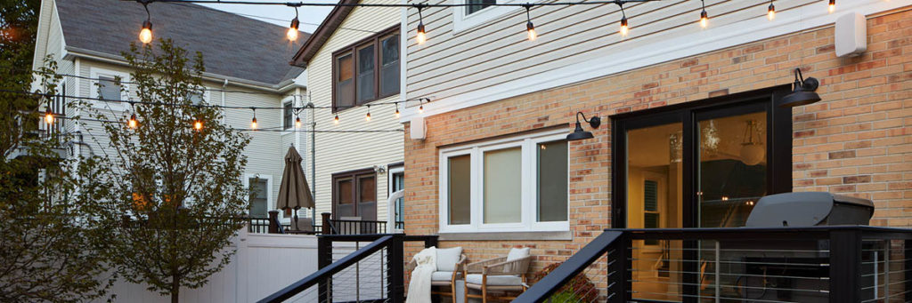 Outdoor deck lighting ideas include string lights hung above a small composite deck