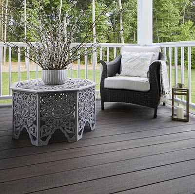 A composite deck features an elegant outdoor chair and ornate coffee table