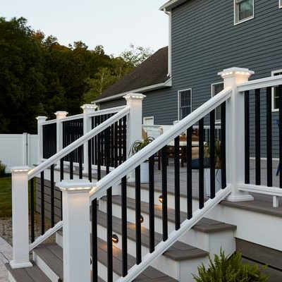 White composite deck railing with black balusters along a gray composite deck