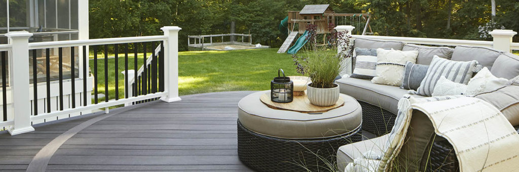 A composite deck made with Dark Hickory multi-width decking features a curved couch