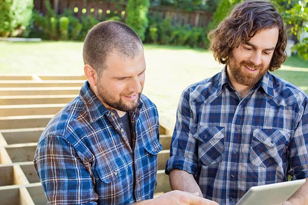 Local deck contractors stand and talk in front of a deck substructure