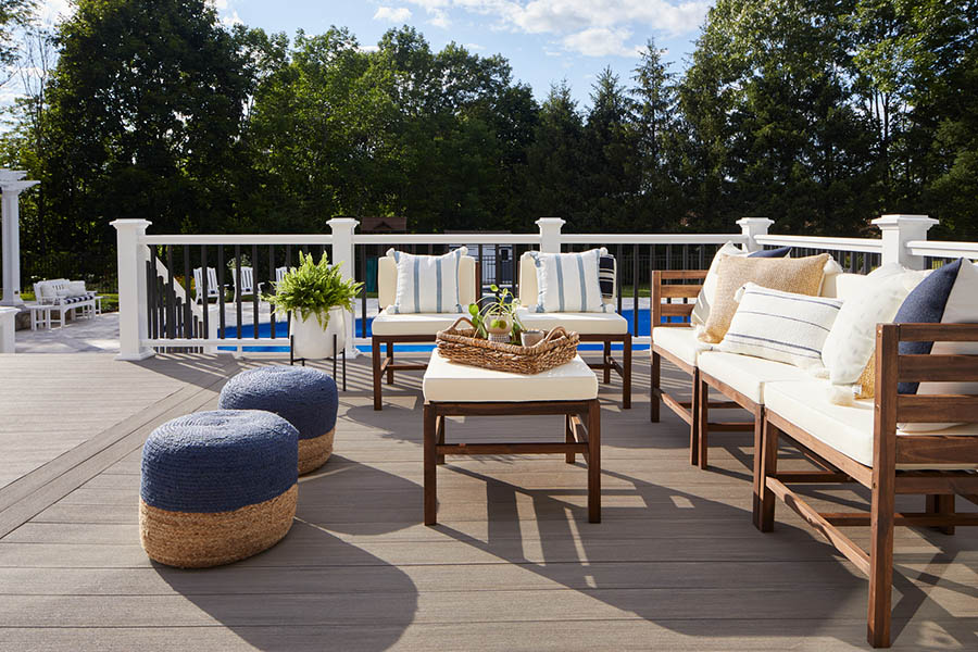 Backyard deck design ideas include a two-tone railing along a coastal style deck