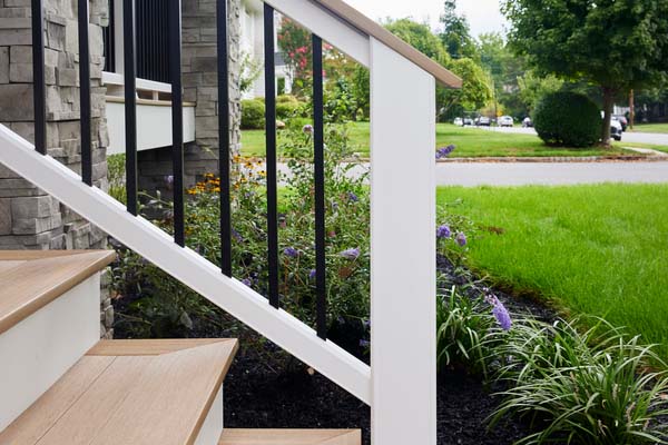 A composite railing with a deck board top rail, matte white posts, and black aluminum balusters