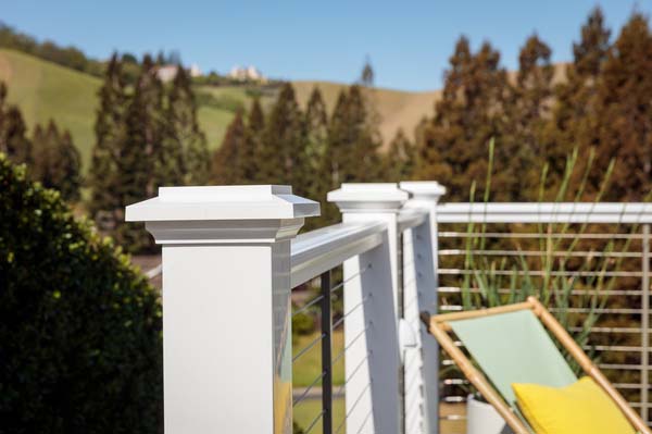 A bright white composite railing with cable infill on a high rise deck overlooking a California landscape