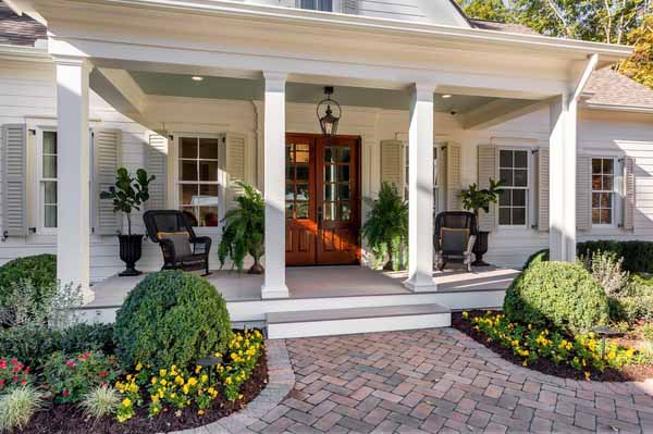 A southern-style home features a small, low porch featuring AZEK Exteriors column wraps