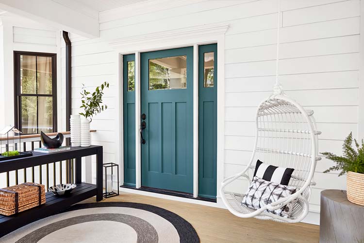 A Scandinavian-style porch features black and white decor with a bright blue door