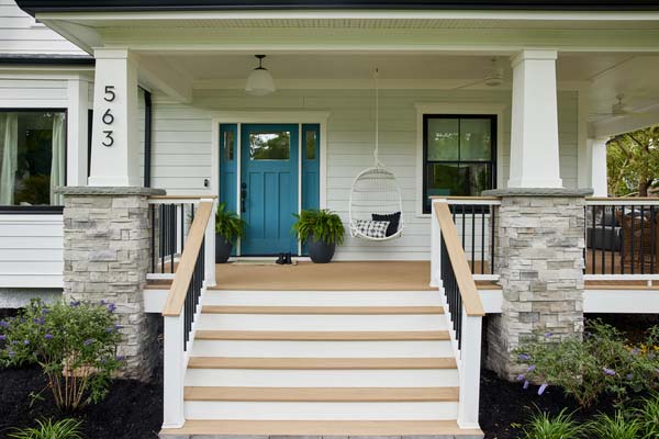 A porch with wide stairs and a Drink Rail features a bright blue door as a focal point