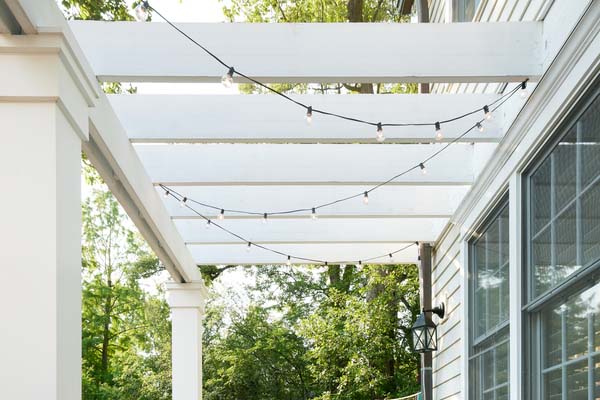 Rooftop deck ideas include string lights hung from a pergola